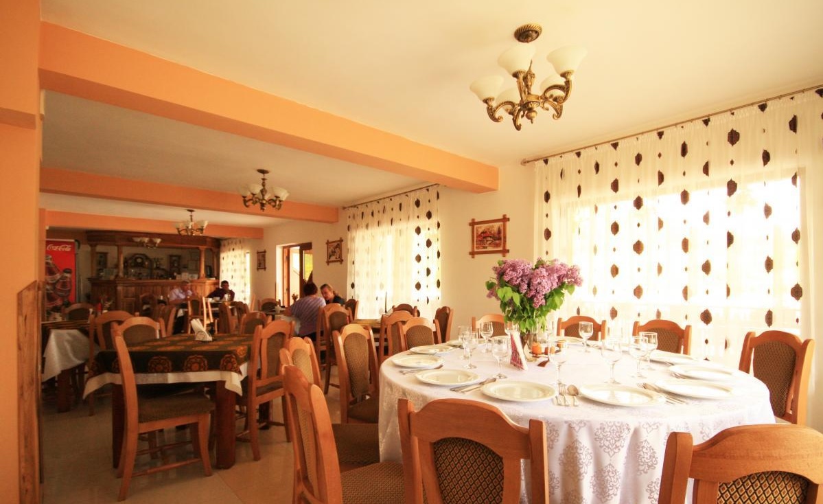 Sala restaurantului, cu mese pregătite și flori proaspete